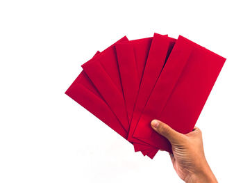 Close-up of hand holding paper against white background