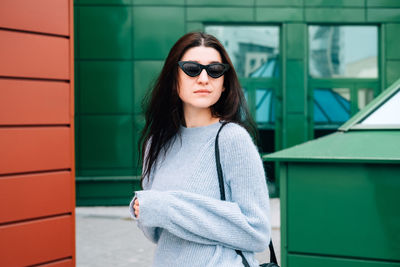 Portrait of young woman wearing sunglasses standing outdoors