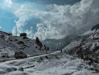 Scenic view of snow covered mountains against cloudy sky