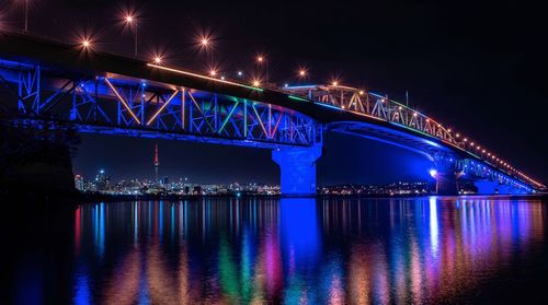 Low angle view of illuminated bridge over river at night