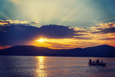 Silhouette sailboat in sea against sky during sunset