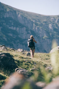 Rear view of woman walking on mountain against clear sky