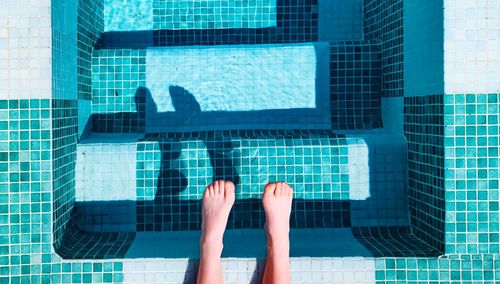 Low section of woman relaxing in swimming pool