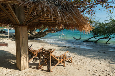  armchairs under straw parasol by turquoise sea, ko man klang, rayong, thailand. travel destination