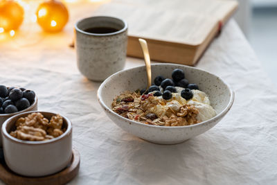 Reading book and eating healthy christmas holiday winter breakfast with granola muesli and yogurt