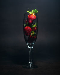 Close-up of strawberries on glass table against black background