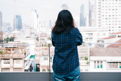 Rear view of woman standing against buildings in city