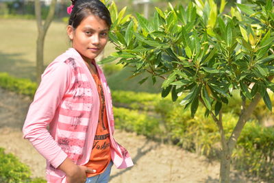 Mid adult woman standing against plants