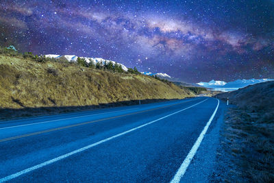 Road by mountains against sky at night