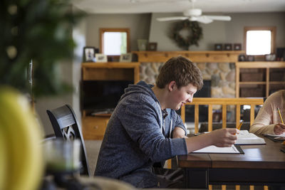 Side view of young man using mobile phone at home