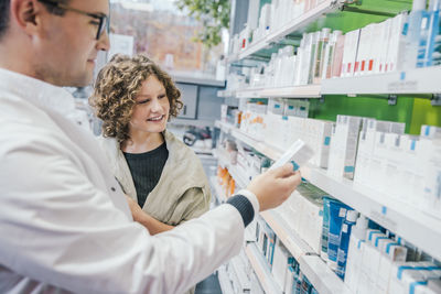 Pharmacist recommending medicine to smiling customer in chemist shop