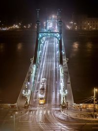Light trails on road by illuminated city at night
