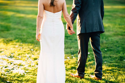Rear view of couple holding hands while standing on field