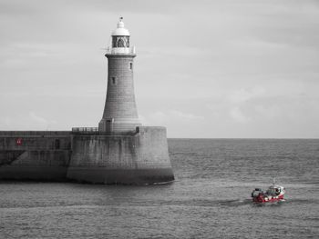 Low angle view of silhouette lighthouse by sea against sky