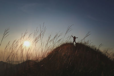 Silhouette man standing on field against sky during sunset