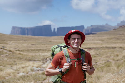 Young man standing on field against sky hiking