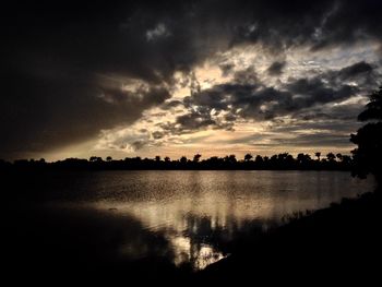 Scenic view of dramatic sky over silhouette trees during sunset