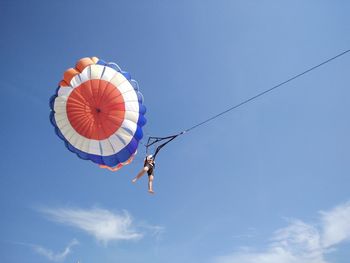 Low angle view of person parasailing against blue sky