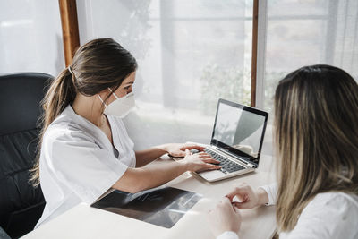 Woman using phone while sitting on table