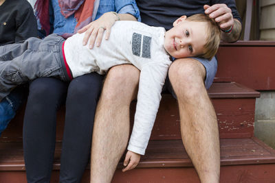 A small child rests on his parents laps outside