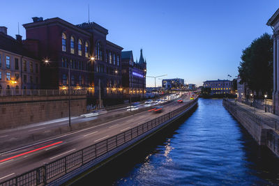 Illuminated city against clear blue sky at night