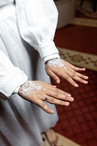 Close up of white henna arts on the bride's hand. bride's hands in shape of love heart - image