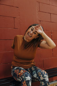 Portrait of happy female athlete sitting on bench during break time at sports court