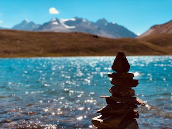 Stack of stones against lake and sky