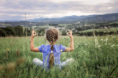 Rear view of boy on field against sky