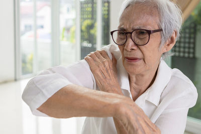 Senior woman touching shoulder