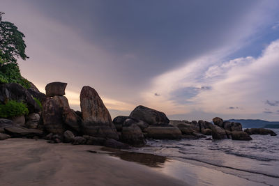 Rocks on beach against sky during sunset