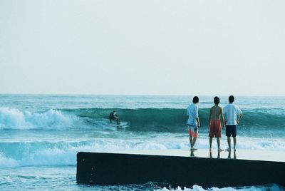 Men standing on beach against clear sky