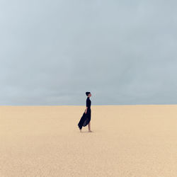 Stylish girl in black clothes walking in the desert