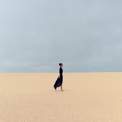 Side view of man on desert against sky