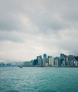 Sea by cityscape against sky