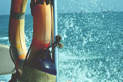 Buoy and life belt tied up on pole by sea