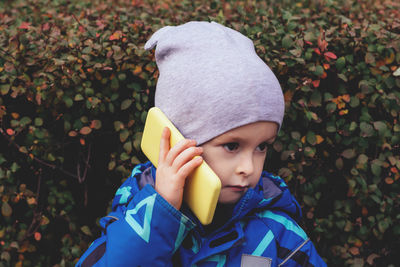 Portrait of a child with a phone in his hands, who looks to the side. childhood communication