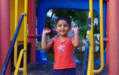 Portrait of happy boy playing on slide at playground