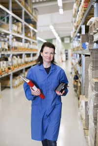 Portrait of woman holding camera while standing in building