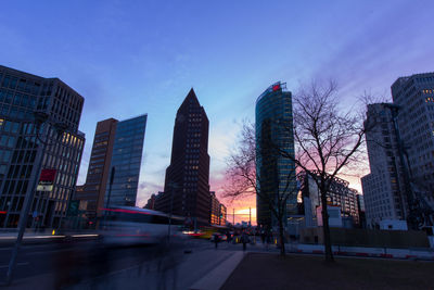 Low angle view of skyscrapers lit up against sky