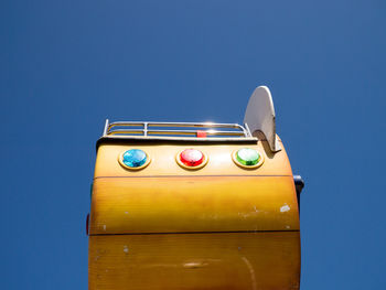 Low angle view of yellow car against blue sky