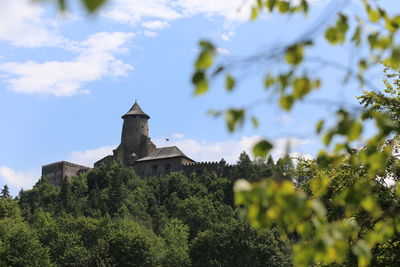 Low angle view of trees and building against sky