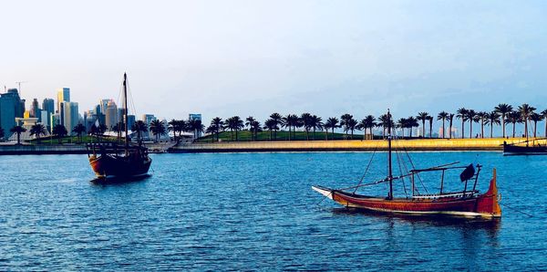 Sailboats in sea against sky in city