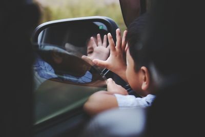 Boy reflection on side-view mirror of car