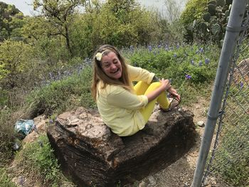 Cheerful woman sitting on rock