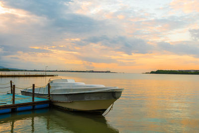 Boat moored in sea against sky during sunset