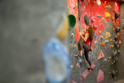 Side view of strong female athlete in sportswear clambering wall in modern bouldering center
