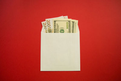 Close-up of paper currency in envelope against red background