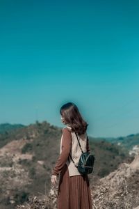Rear view of woman standing against clear sky