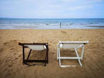 Chairs at beach against sky